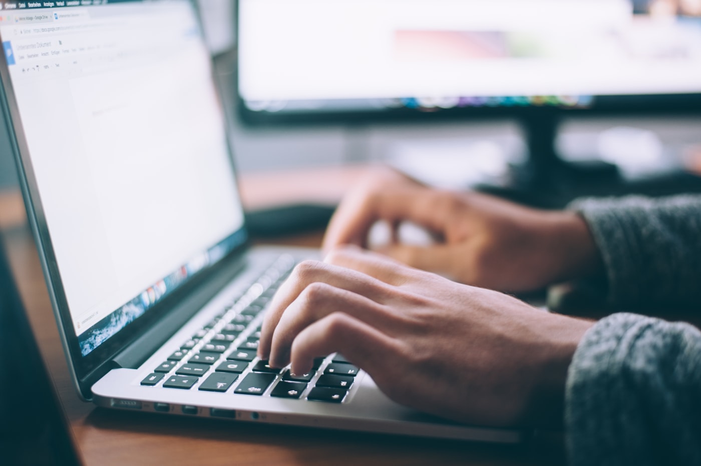 Persona al telefono con notebook aperto sulla scrivania
